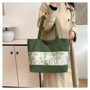 Détail du cabas en toile verte avec imprimés de feuilles de bambou et trench-coat chic