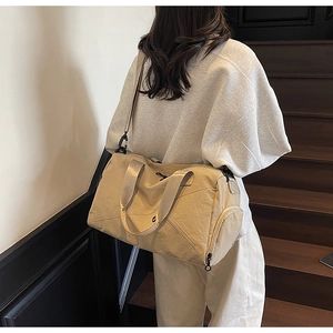 Detail view of large beige canvas travel bag with shoe compartment on wooden stairs