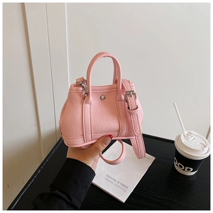 Detail of light pink mini handbag featuring litchi grain texture and silver metal studs