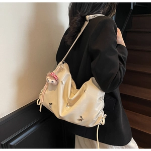 Detail of off-white pleated crossbody bag with silver butterflies and a pink plush charm