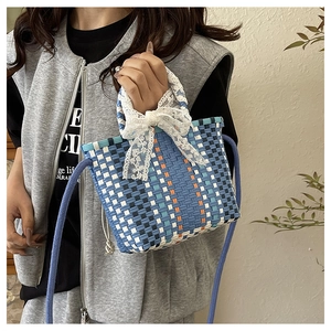 Detail of woven crossbody bag featuring a multi-color pattern and white lace bow accessory