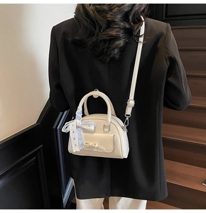Detail of cream PU leather handbag with bow pocket and plaid ribbon handle on model