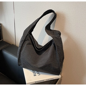 Detail of black and white checkered canvas tote bag on a sofa with minimalist texture