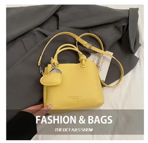 Détail du sac seau en cuir grainé jaune avec poignées nouées et breloque en forme de cœur