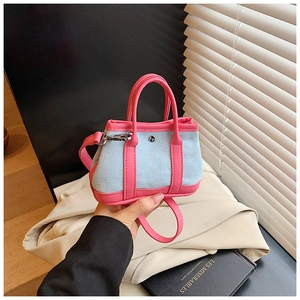 Detail of mini denim handbag with peach pink leather trim and silver metal hardware