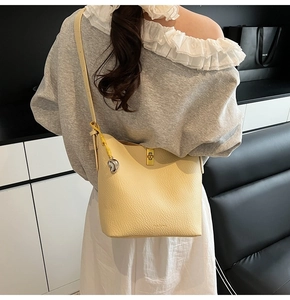 Chic beige bucket bag styled with gray blouse showing everyday wear and gold hardware
