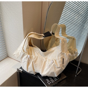 Detail of off-white nylon crossbody bag with drawstring pockets and adjustable buckle strap