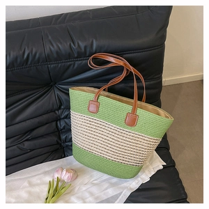 Dettaglio borsa tote in paglia intrecciata verde e bianca con manici in pelle marrone