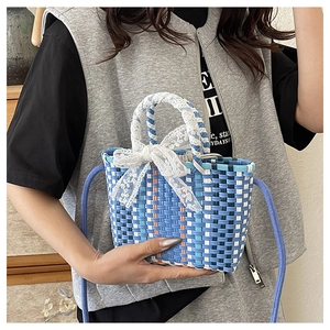 Detail of multi-color woven bucket bag with lace bow and blue shoulder strap