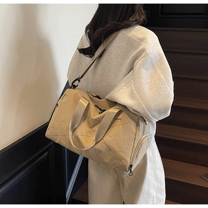 Detail view of khaki waterproof travel bag with adjustable strap and zip pocket