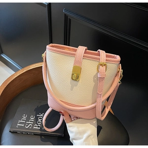 Détail du sac seau en cuir rose et beige avec fermoir doré et texture grainée