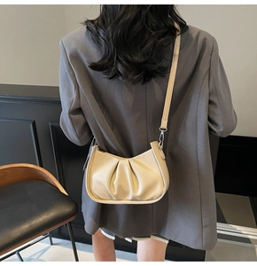 Detail of beige pleated faux leather texture and adjustable strap on a shoulder bag
