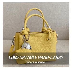 Détail du sac seau en cuir jaune avec poignée en corde nouée et pendentifs en métal