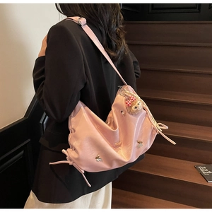 Detail of pink soft leather hobo bag with 3D metal butterflies and plush monkey charm