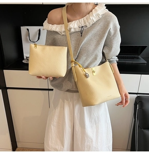 Detail of light yellow lychee pattern leather bucket bag with gold hardware and pony charm