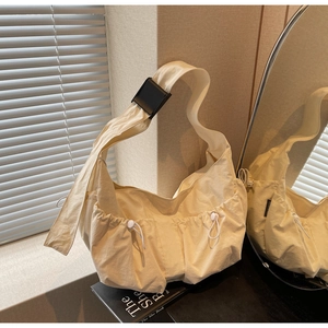 Detail of beige nylon crescent bag featuring functional drawstring pockets and adjustable strap