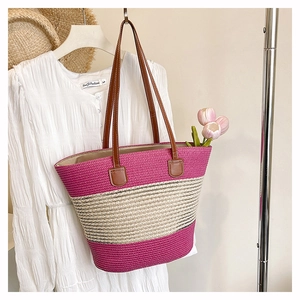 Dettaglio della borsa tote in paglia intrecciata con strisce rosa e manici in pelle per l'estate