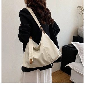 Detailed side view of the large pleated canvas tote bag on model's shoulder in interior