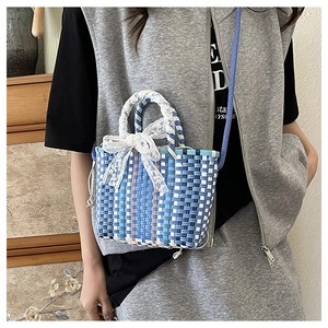 Detail of blue and white woven tote bag featuring a white lace bow and orange side accents
