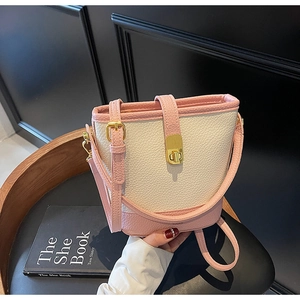 Détail du sac seau bicolore rose et beige en cuir avec des boucles dorées