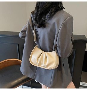 Detailed back view of a beige pleated hobo bag worn with a professional grey blazer