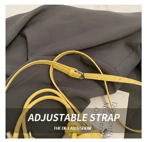 Détail d'un sac seau en cuir jaune avec bandoulière réglable et boucle en argent