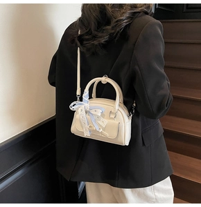 Detail of cream mini shoulder bag featuring a blue checkered ribbon and lace handle decoration