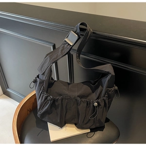 Detail of black nylon dumpling bag with multi-pocket drawstring and adjustable strap