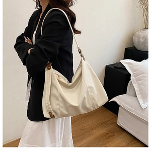 Chic beige ruched tote bag worn over the shoulder with comfortable wide strap
