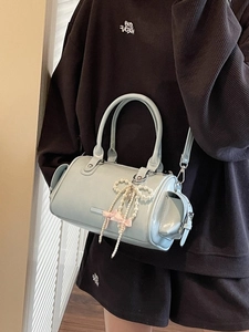Borsa Boston azzurra con ciondolo a fiocco di perle e tracolla indossata da una modella