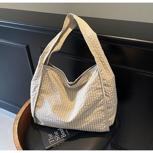 Detail showing the textured plaid pattern and wide shoulder strap of the large tote bag
