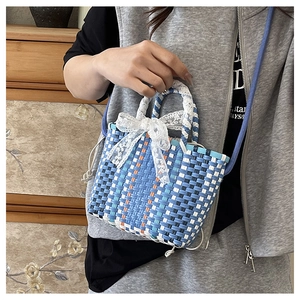 Detail of multi-color woven crossbody bag with white lace bow and blue braided strap
