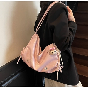 Detail of pink pleated cloud bag with metal butterfly and side drawstring knots