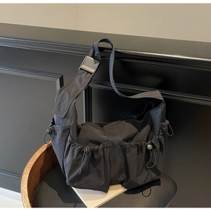 Detail of black nylon dumpling bag featuring adjustable drawstring utility pockets