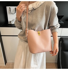 Close-up of pink bucket bag with gold twist lock and adjustable leather shoulder strap