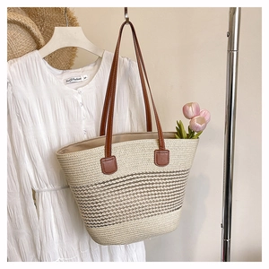 Dettaglio della borsa tote in paglia intrecciata con manici in pelle marrone