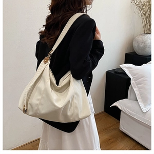 Detail showing the creamy white hobo bag with a gold metal ring buckle and wide shoulder strap