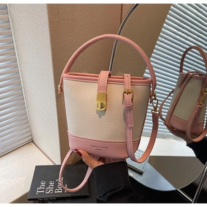 Détail d'un sac seau bicolore en cuir rose et crème avec fermoir doré élégant