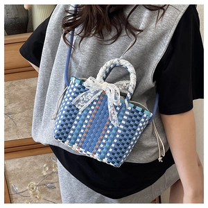 Detail of hand-woven mini tote bag with lace bow and blue crossbody strap