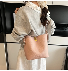 Detail of pink pebbled leather bucket bag with gold twist lock and heart charm pendant