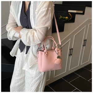 Détail du sac seau rose cerise en cuir grainé avec pendentif coeur et bandoulière