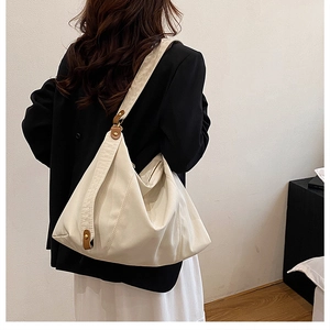 Detail view of cream canvas hobo bag showing brown leather buckle on modern minimalist model