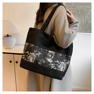 Détail d'un grand sac cabas en toile noire avec imprimé bambou gris porté à l'épaule