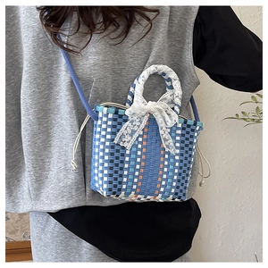 Close-up of blue woven crossbody bag with white lace bow and drawstring closure