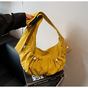 Detailed close-up of yellow pleated nylon bag showing drawstring and buckle texture