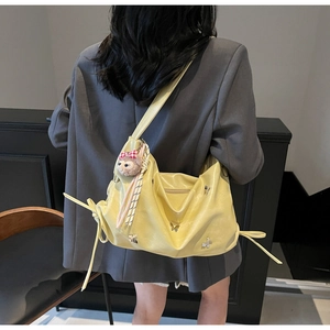 Detail of yellow pleated shoulder bag with bow ribbons and metal butterfly charm