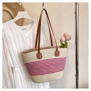 Dettaglio della borsa tote in paglia intrecciata con strisce rosa e manici in pelle marrone