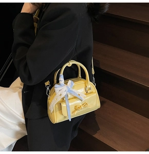 Detail of bright yellow mirrored PU leather crossbody bag with blue checkered bow decoration