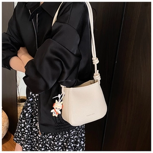 Detail of off-white bucket bag featuring knotted strap and cute bunny pendant charm