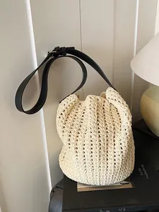 Chic cream woven bucket bag with black leather shoulder strap for elegant daily styling
